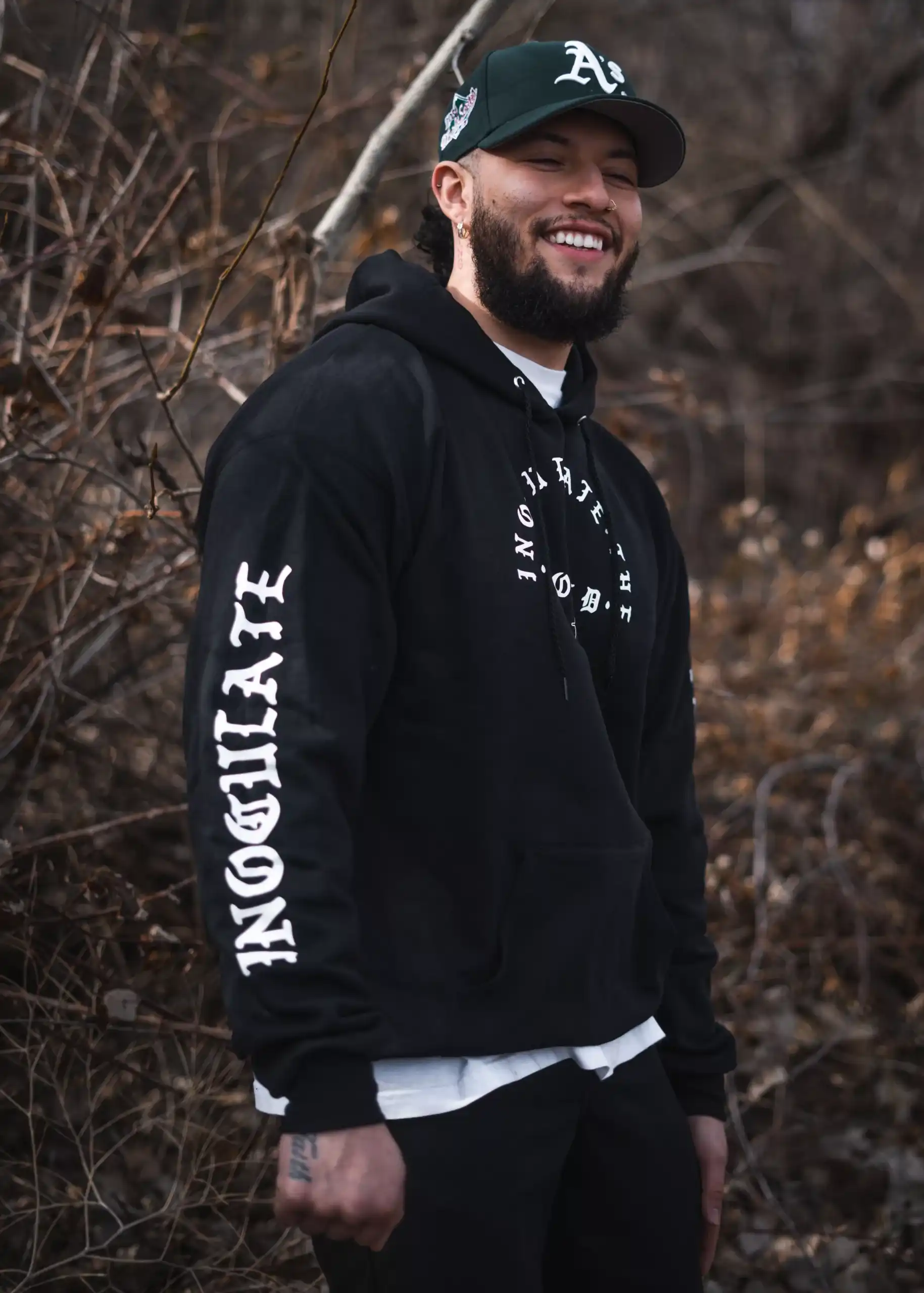 A man wearing a black hoodie with white gothic text. 